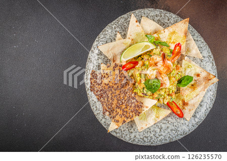 delicious guacamole, nachos chips and shrimp. Classic Tex-Mex restaurant appetizer on a dark background. top view. copy space for text 126235570