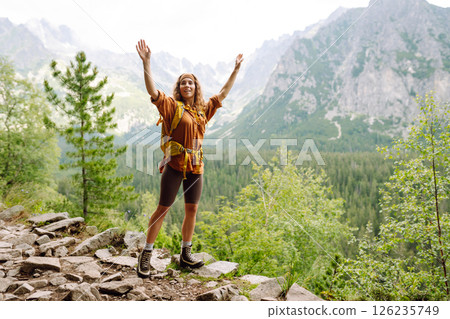 Young traveler woman with a yellow backpack on a cliff. Sports concept, traveler. Active lifestyle. Young traveler woman with a yellow backpack on a cliff. Sports concept, traveler. Active lifestyle. 126235749