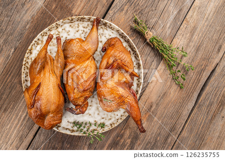Smoked grilled quail meat with thyme on a wooden board Smoked grilled quail meat with thyme on a wooden board 126235755
