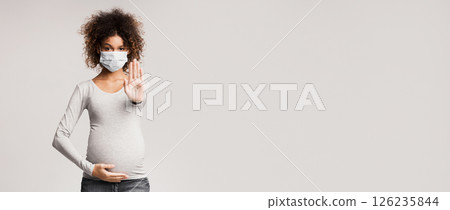 Afro pregnant woman in medical face mask gesturing stop over gray studio background 126235844