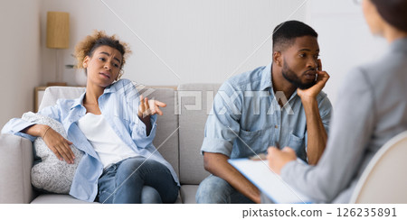 Indifference In Relationship. African American Husband Looking Away While His Indifferent Wife Complaining To Counselor Sitting On Sofa. 126235891