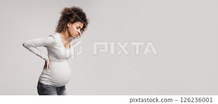 Pregnant woman with contractions, touching her back and suffering from pain, grey background 126236001