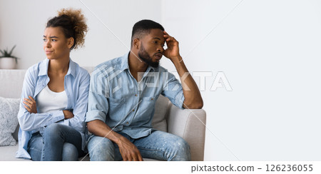 Misunderstanding In Relationship. Frustrated Black Man And Woman Avoiding Eye Contact Sitting On Couch At Home. 126236055