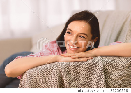 Enjoy Song. Portrait of beautiful pensive lady in headphones lying on sofa and listening to music at home, copyspace 126236218