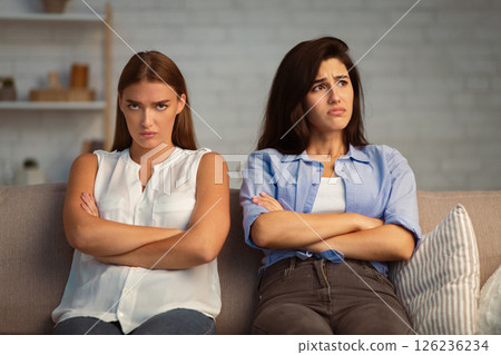Two Angry Offended Women After Quarrel Crossing Arms Sitting On Sofa At Home. Two Angry Offended Women After Quarrel Crossing Arms Sitting On Sofa At Home. 126236234