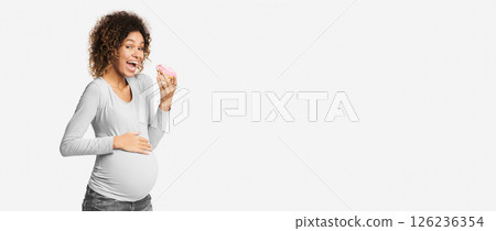 Hungry expectant woman eating donut, standing over white studio background, free space Hungry expectant woman eating donut, standing over white studio background, free space 126236354