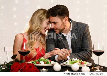 Couple in love having romantic dinner in restaurant, celebrating anniversary or Valentine's day, embracing and enjoying time together Couple in love having romantic dinner in restaurant, celebrating anniversary or Valentine's day, embracing and enjoying time together 126236399