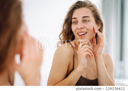 Beautiful woman with acne problem skin checks dry face skin. Red spots, rash, acne. Skin treatment. 126236412