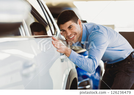 Happy Car Buyer. Excited Young Guy Touching His New Auto In Dealership Showroom. Selective Focus 126236479