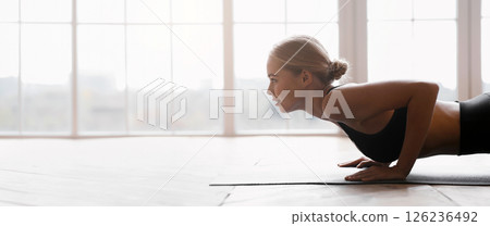 Half body of blonde yoga girl exercising on wooden floor over panoramic window, free space 126236492