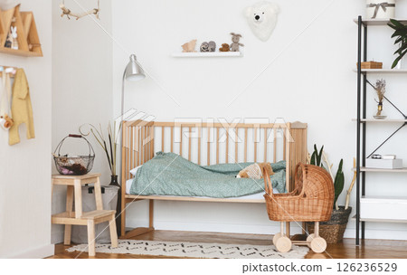 Baby Bedroom Interior with Cozy Wooden Bed, Wicker Stroller and Rack In Scandinavian Style 126236529