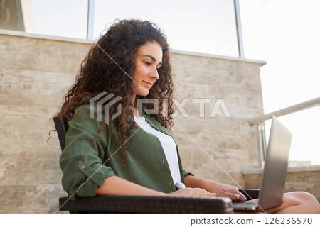 Pretty curly women works at laptop sitting, work online, shopping online, communication in social networks, online learning, freelancer Pretty curly women works at laptop sitting, work online, shopping online, communication in social networks, online learning, freelancer 126236570
