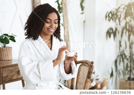 Skin Care Routine. Beautiful Black Girl After Showering Applying Moisturising Cream On Face, Holding Jar With Hydrating Lotion, Free Space Skin Care Routine. Beautiful Black Girl After Showering Applying Moisturising Cream On Face, Holding Jar With Hydrating Lotion, Free Space 126236636