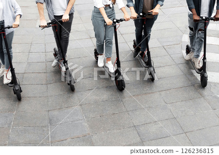 Eco Friendly Transport. Five cheerful smiling multiethnic friends riding e-scooters, high angle view Eco Friendly Transport. Five cheerful smiling multiethnic friends riding e-scooters, high angle view 126236815