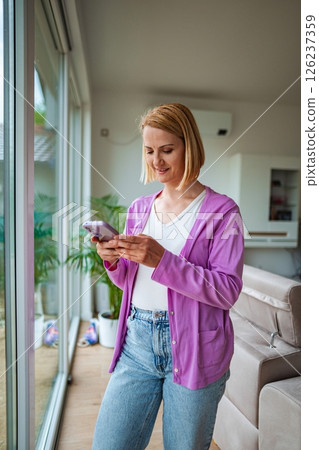 Woman texting in cozy modern living room 126237359