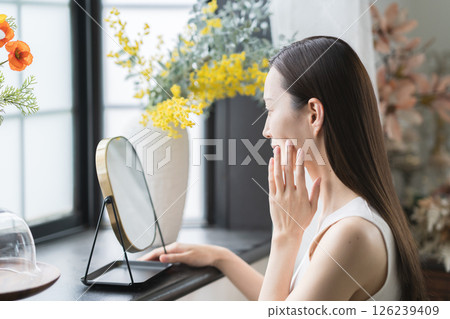 微笑的女人在鏡子裡檢查自己的皮膚 微笑的女人在鏡子裡檢查自己的皮膚 126239409