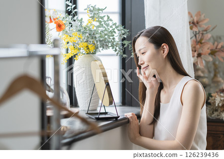 Smiling woman checking her skin in the mirror 126239436
