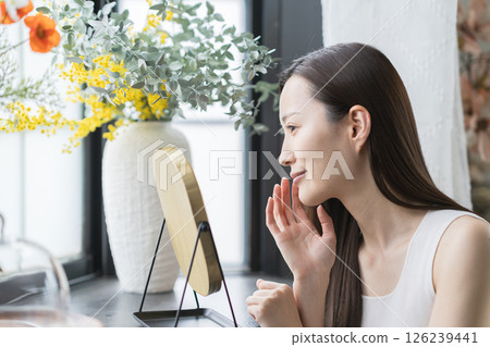 Smiling woman checking her skin in the mirror Smiling woman checking her skin in the mirror 126239441