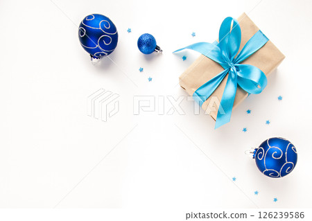 on a light background a gift with a blue ribbon, a fir branch and blue ornaments on a light background a gift with a blue ribbon, a fir branch and blue ornaments 126239586