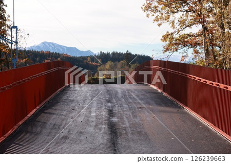 A bridge with a red railing and a view of the mountains 126239663