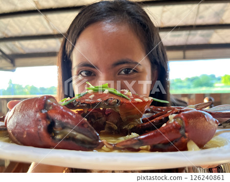 young asian woman showing off crab on plate peeking out from behind crab 126240861
