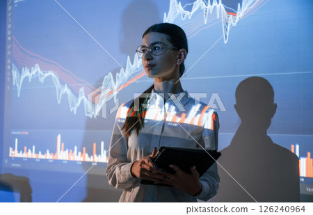 Woman is standing near projector with the finance graphs Woman is standing near projector with the finance graphs 126240964