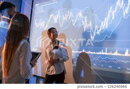 Exchange company. Female leader talking to employees, showing the plan on the projector in office of stock 126240966