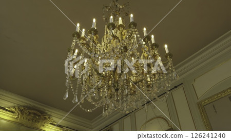 Elegant crystal chandelier illuminating ornate palace room. Action 126241240