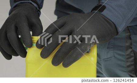 Careful and Professional Handling of the Yellow Bottle using Protective Gloves and Gear. Creative Careful and Professional Handling of the Yellow Bottle using Protective Gloves and Gear. Creative 126241454