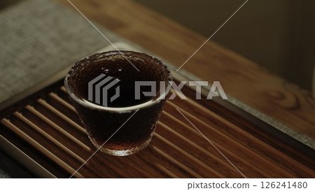 Pouring tea into a textured glass cup creates a calm atmosphere and showcases handcrafted luxury. Media 126241480