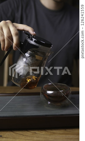 A Beautifully Brewed Tea is Being Poured from a Pitcher into a Transparent Glass Bowl. Media 126241559