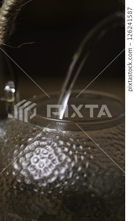 An Elegant Water Pouring into a Beautiful Glass Teapot with Grace and Refinement. Media An Elegant Water Pouring into a Beautiful Glass Teapot with Grace and Refinement. Media 126241587