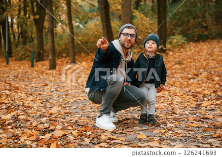 In the autumn forest. Father and young son is together outdoors at daytime In the autumn forest. Father and young son is together outdoors at daytime 126241693
