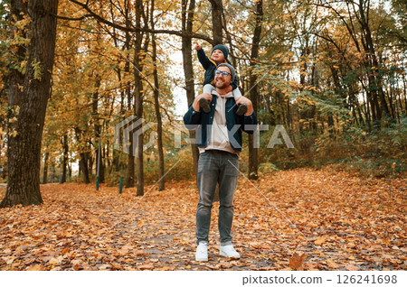 Having a walk in forest. Father and young son is together outdoors at daytime 126241698