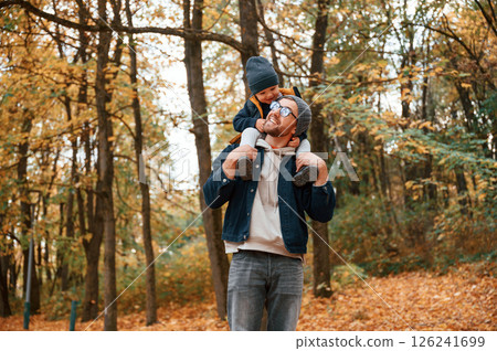 Having a walk in forest. Father and young son is together outdoors at daytime Having a walk in forest. Father and young son is together outdoors at daytime 126241699