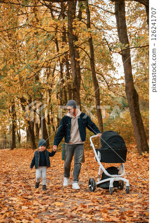 With pram. Father and young son is together outdoors at daytime With pram. Father and young son is together outdoors at daytime 126241707