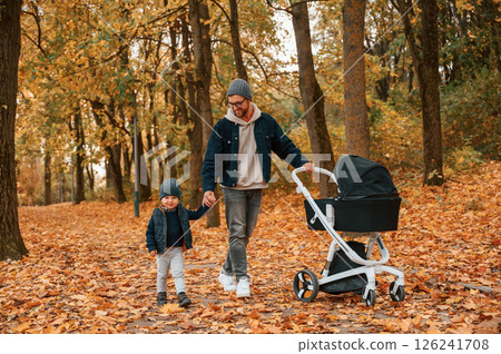 With pram. Father and young son is together outdoors at daytime With pram. Father and young son is together outdoors at daytime 126241708
