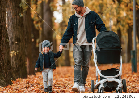 With pram. Father and young son is together outdoors at daytime With pram. Father and young son is together outdoors at daytime 126241863