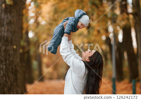 Beautiful mother holding her little son in hands. Standing in the autumn forest 126242172