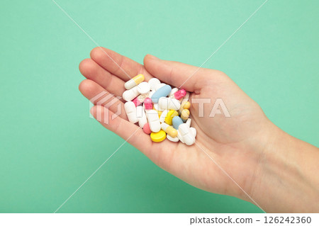 Colorful pills and medicines in the hand on mint background Colorful pills and medicines in the hand on mint background 126242360