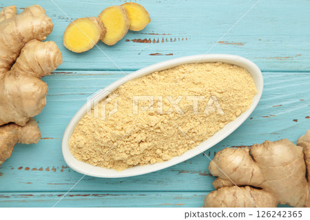 Ginger powder on white plate with fresh ginger root on blue wooden background. Top view Ginger powder on white plate with fresh ginger root on blue wooden background. Top view 126242365