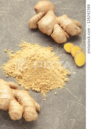 Ginger powder with fresh ginger root on grey concrete background. Top view Ginger powder with fresh ginger root on grey concrete background. Top view 126242366