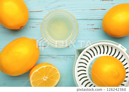 Squeezer and lemons juice on blue wooden background Squeezer and lemons juice on blue wooden background 126242368