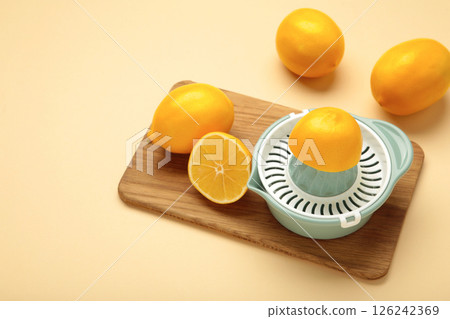 Squeezer and lemons on cutting board on beige background 126242369