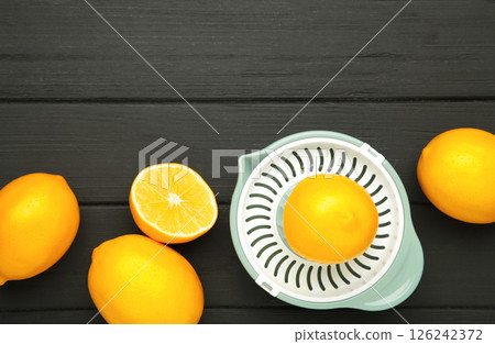 Wooden hand juicer and cut lemons on black wooden background. Squeezing lemons for lemonade or food preparation. 126242372