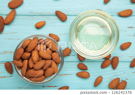 Almond oil with almond nuts in two glass bowl on blue wooden background. 126242376