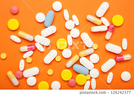Various colored pills on orange background. Space for text 126242377