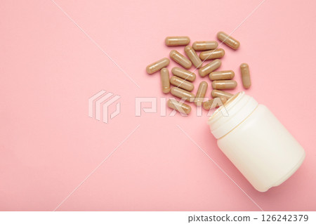 Beige pharmaceutical medicine pills and bottle on pink background. Vertical photo Beige pharmaceutical medicine pills and bottle on pink background. Vertical photo 126242379