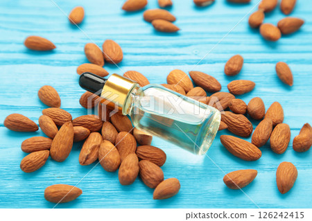 Fresh almond oil with almond nuts on blue wooden background. Fresh almond oil with almond nuts on blue wooden background. 126242415