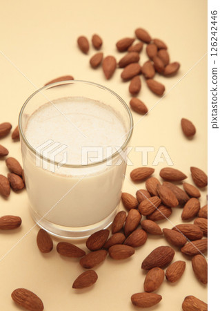 Fresh almond milk in glass and almonds on beige background. Healthy vegan plant based alternative milk replacer. Vertical photo Fresh almond milk in glass and almonds on beige background. Healthy vegan plant based alternative milk replacer. Vertical photo 126242446